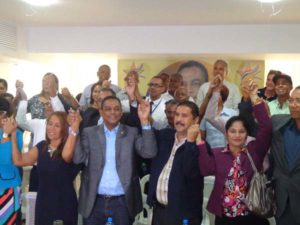 El diputado Ramón Cabrera y el dirigente Freddy Santana levantan las manos junto a decenas de miembros del PLD de la Circunscripción número 2 de Santo Domingo Este.  