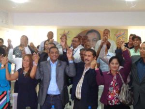 El diputado Ramón Cabrera y el dirigente Freddy Santana levantan las manos junto a decenas de miembros del PLD de la Circunscripción número 2 de Santo Domingo Este.
