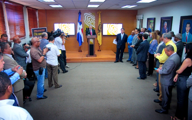 El director de Comunicaciones de la JCE, Félix Reyna, explica el concepto de la nueva campaña electoral de la institución. Observan los magistrados Rosario Graciano de los Santos, José Ángel Aquino Rodríguez y César Francisco Féliz Féliz, miembros titulares, y los doctores Juan Moreno y Ramón Hilario Espiñeira, suplente del presidente de la JCE y secretario general respectivamente, entre otros funcionarios de la institución.